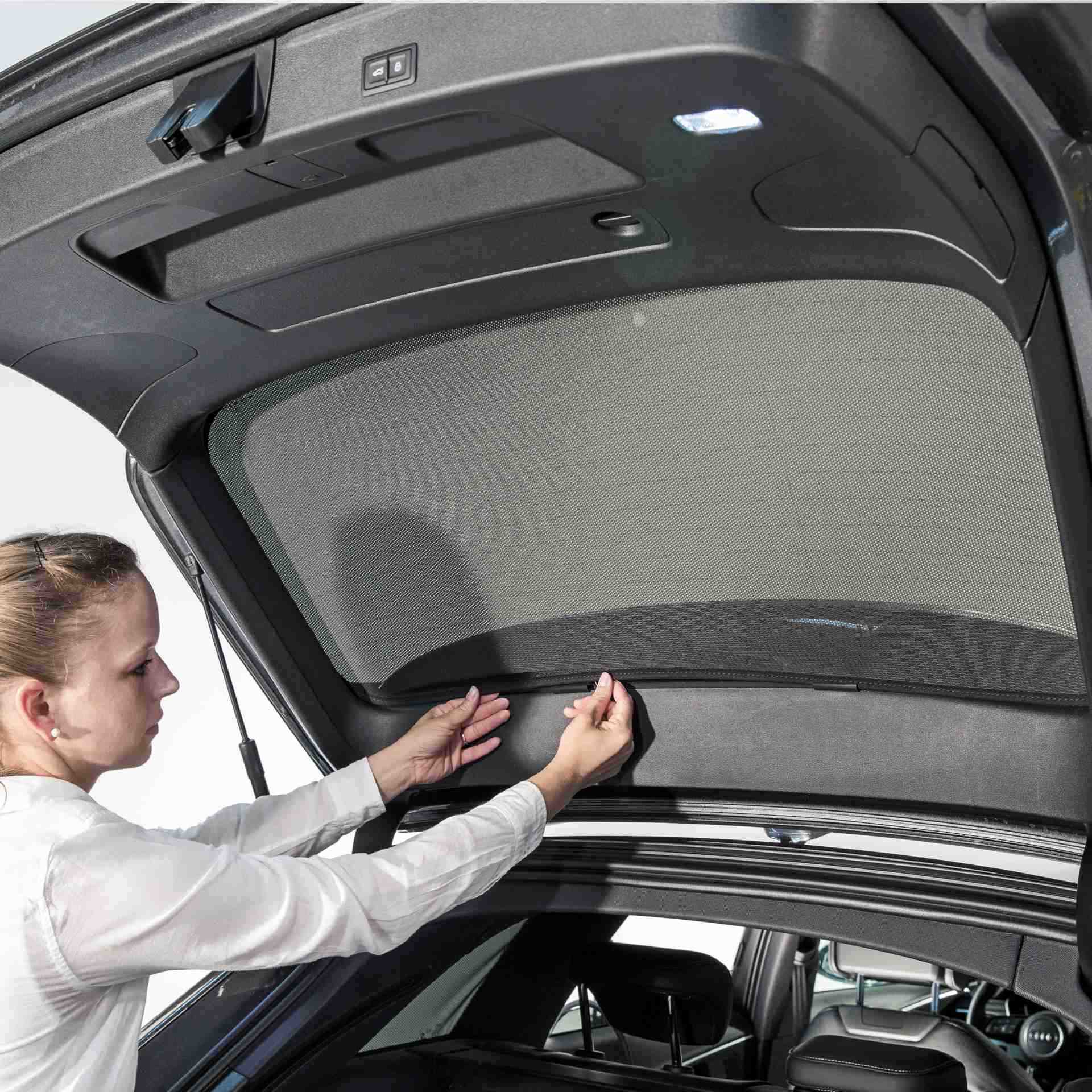 a woman installs a SunClip to the rear window of a car