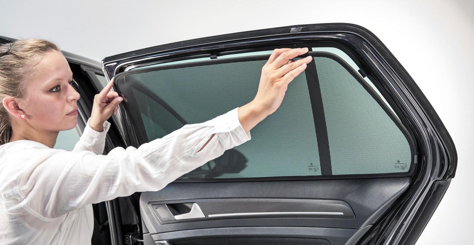 eine Frau bringt eine Sonnenblende an einem Autofenster an