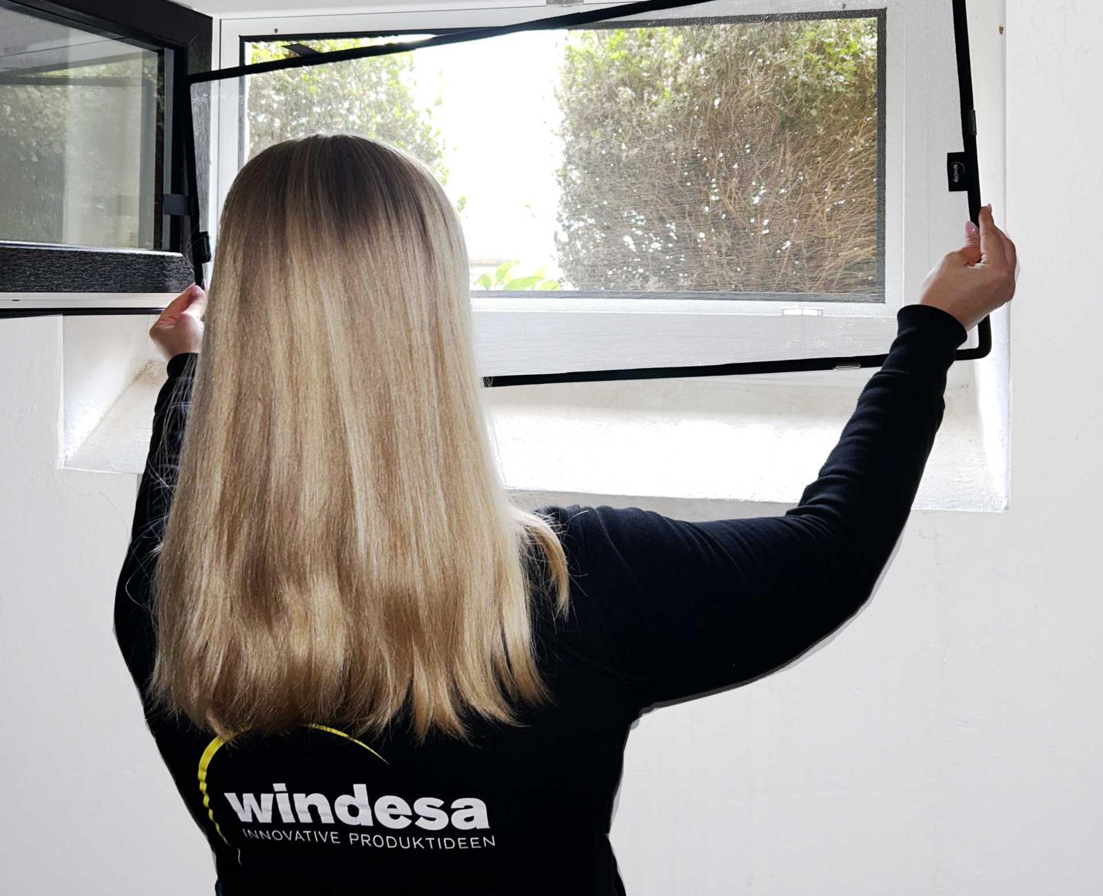 >> WinClip Safe Story & Shop >> eine Frau hält einen Nageschutz an ein Kellerfenster